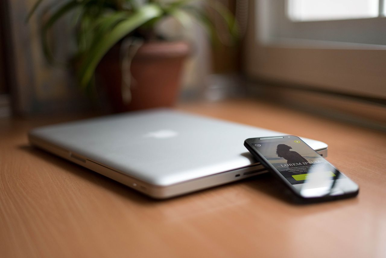 services-02 Close-up of a silver laptop and smartphone on a wooden desk, capturing modern work essentials.